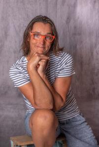 portrait d'une femme assise sur un escabeau en bois ses mains tiennent sa tête photographe de portrait- krystyne ramon - home studio photos