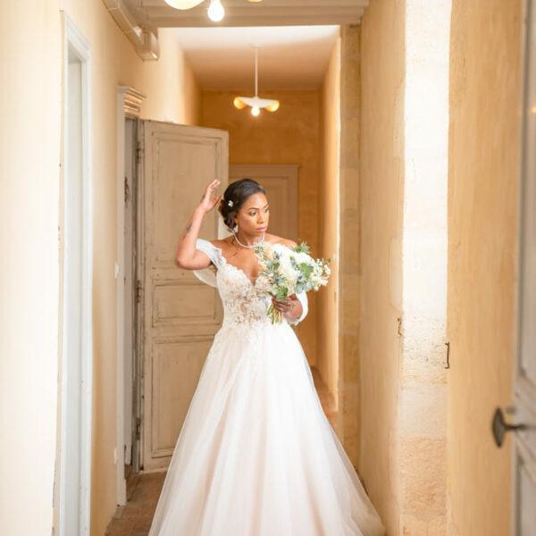 mariée dans un couloir aux tons dorés la main posée sur son chignon- photographe de mariage- krystyne ramon