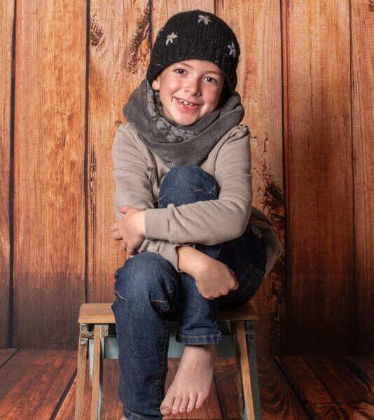 portrait d'un jeune garçon avec une écharpe un bonnet assis sur un tabouret krystyne ramon - home studio photos