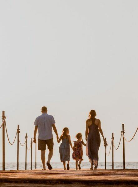 Séance photo famille sur un ponton a la plage 2 fillettes entre leurs parents -photographe de famille