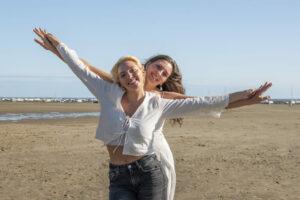 Séance photo portrait sur la plage de 2 sœurs les bras en l'air photographe de portrait- krystyne ramon - home studio photos