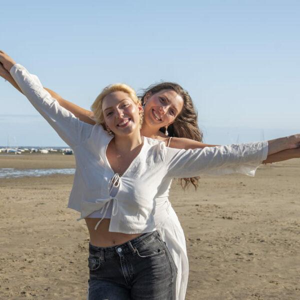 Séance photo portrait sur la plage de 2 sœurs les bras en l'air photographe de portrait- krystyne ramon - home studio photos