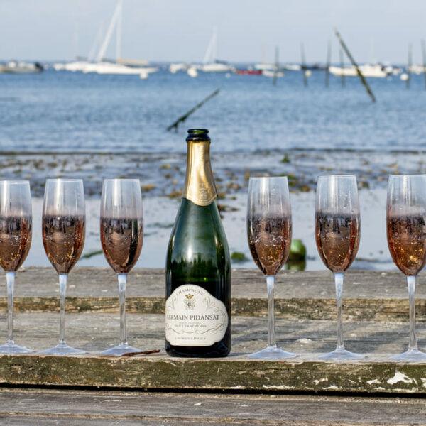 séance EVJF huit verres de champagne au milieu d'une bouteille posés sur une murette devant la mer krystyne ramon - home studio photos