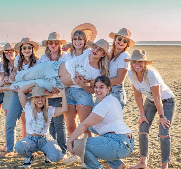séance EVJF groupe de neufs jeunes filles sur la plage qui portent la future mariée krystyne ramon - home studio photos