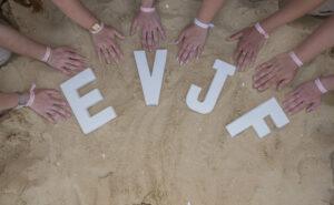 séance EVJF huit mains posées sur le sable en arc de cercle avec les lettres EVJF également sur le sable