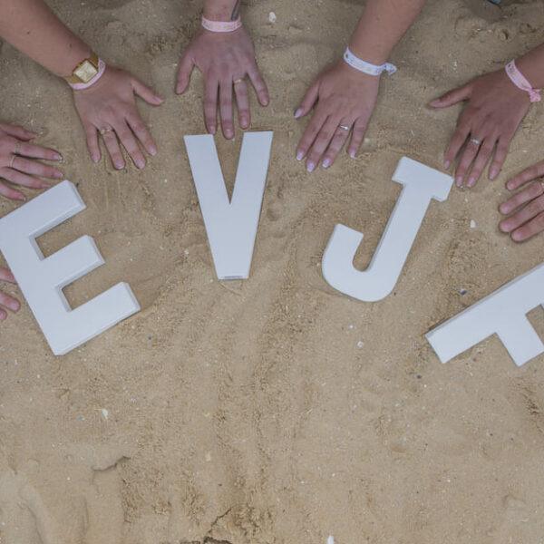 séance EVJF huit mains posées sur le sable en arc de cercle avec les lettres EVJF également sur le sable krystyne ramon - home studio photos