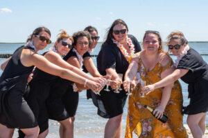 séance EVJF groupe de sept jeunes filles en arc de cercle le bras tendu avec une coupe de champagne a la main