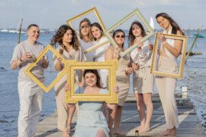 séance EVJF groupe de 8 personne sur un bateau les têtes dans des cadres dores et une coupe de champagne dans la main