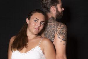 Portrait d'un jeune couple dos a dos lui est torse nu avec des tatouages photographe de portrait- krystyne ramon - home studio photos