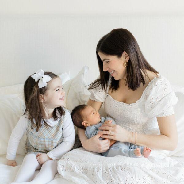 Séance naissance bebe dans les bras de sa maman avec la grande soeur a coté.-photographe de naissance-