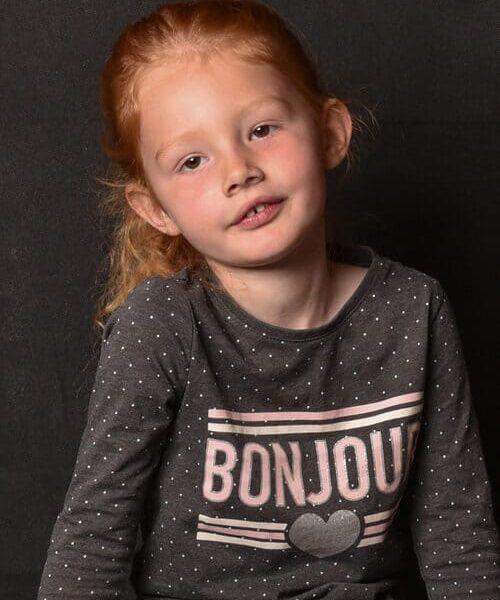 portrait d'une petite fille rousse assise la tête penchée krystyne ramon - home studio photos