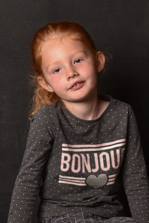 portrait d'une petite fille rousse assise la tête penchée krystyne ramon - home studio photos