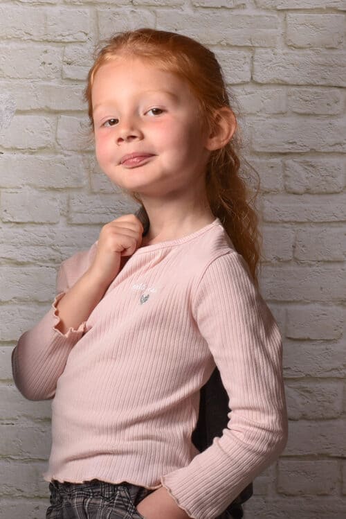 portrait d'une petite fille rousse de profil tenant une veste sur une épaule krystyne ramon - home studio photos