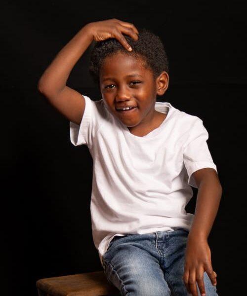 portrait enfant garçon de couleur assis sur un escabeau en bois faisant le singe krystyne ramon - home studio photos