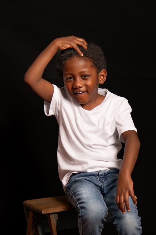 portrait enfant garçon de couleur assis sur un escabeau en bois faisant le singe krystyne ramon - home studio photos