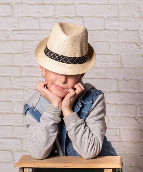 portrait du jeune garçon avec un chapeau on ne lui voit pas les yeux il est accoudé sue un escabeau krystyne ramon - home studio photos