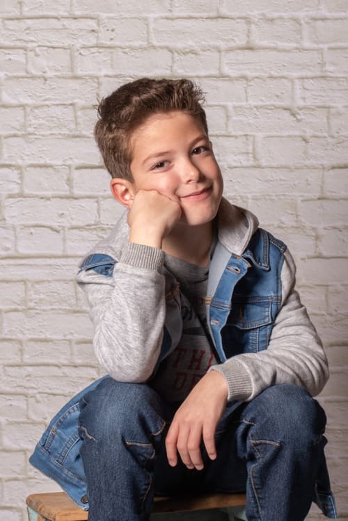 portrait du jeune garçon assis sur un escabeau le bras accoudé sur un genou krystyne ramon - home studio photos