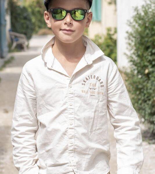 portrait enfant jeune garçon marche dans une ruelle d'un village casquette lunette de soleil une main dans sa poche de pantalon photographe d'enfants- krystyne ramon - home studio photos