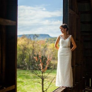 mariée debout dans une grange regarde au loin - photographe de mariage-